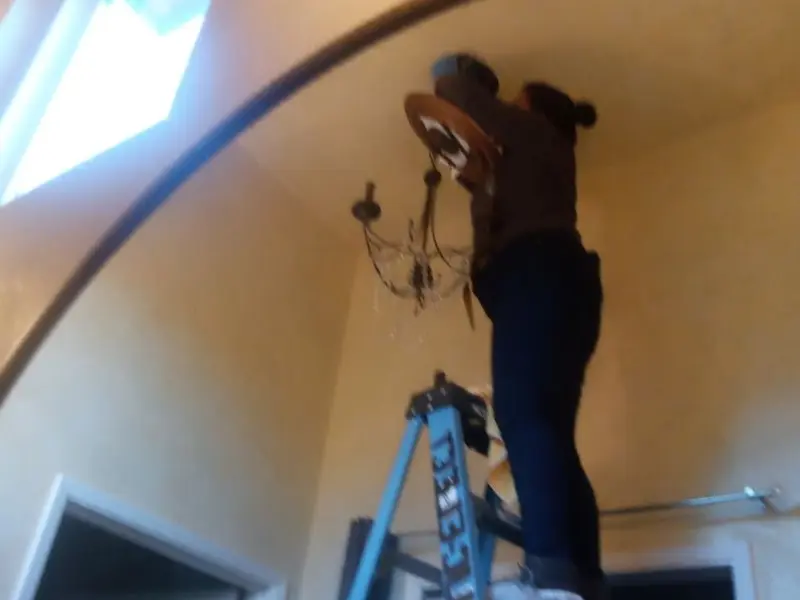 Electrician installing a chandelier in a Long Beach residence
